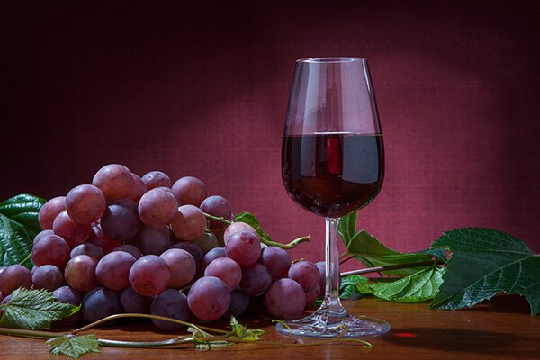 На винтажной картинке бокал красного Портвейна с кистью винограда